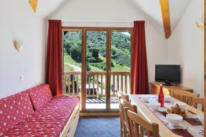 sala de estar con mesa, sofá y TV en Les Hauts de Valmeinier, en Valmeinier