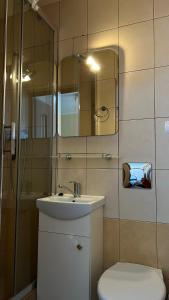 a bathroom with a sink and a toilet and a mirror at Pokoje u Kamy in Ustka