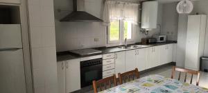 a kitchen with white cabinets and a table with chairs at Area Pequena in Malpica