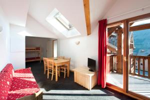 a living room with a couch and a table with a television at Les Hauts de Valmeinier in Valmeinier