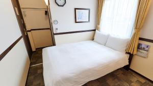 uma pequena cama num quarto com uma janela em Toyoko Inn Hiroshima Ekimae Ohashi Minami em Hiroshima