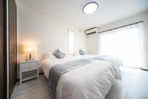 een witte slaapkamer met een bed en een raam bij Awaji Riverside Terrace in Shizuki 780 in Shizuki +44 foto's