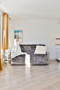 una sala de estar con un sofá gris en una habitación blanca en IMMODREAMS - Le Vivace, en Avoriaz