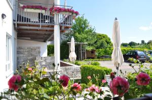 a house with a balcony with pink flowers and umbrellas at Pension Keller in Reichenau