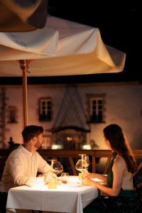 un homme et une femme assis à une table sous un parapluie dans l'établissement Chateau Du Boisniard, à Chambretaud