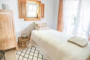 1 dormitorio con cama blanca y ventana en Dreamsea Surf Guest House, en Sintra