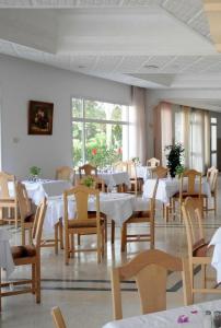 un comedor con mesas blancas y sillas de madera en Hôtel Mechmoum Yasmine Hammamet en Hammamet