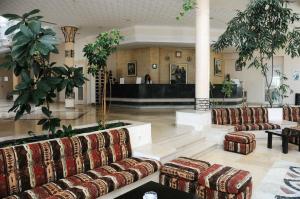 a lobby with couches and plants in a building at Hôtel Mechmoum Yasmine Hammamet in Hammamet