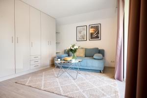 Pension - Ferienwohnungen Zollner في فيلاخ: غرفة معيشة مع أريكة زرقاء وطاولة