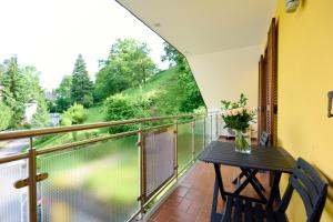 un balcón con una mesa y un jarrón de flores en Pension - Ferienwohnungen Zollner en Villach