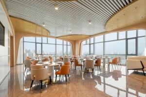 a restaurant with tables and chairs and large windows at Atour Hotel Nantong Longxin Plaza in Nantong