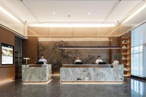 Un vestíbulo con tres personas trabajando en sus computadoras portátiles. en Atour Hotel Tonglu City Center Hangzhou, en Xiaoba