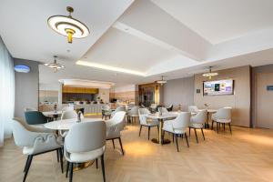 une salle à manger avec des tables et des chaises blanches dans l'établissement Atour Hotel Taizhou Linhai Toumen Port, à Linhai