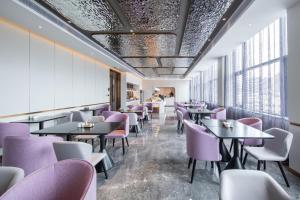 a restaurant with purple chairs and tables and windows at Atour Light Hotel Huizhou Jinshanhu Ganghui in Huizhou