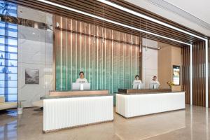 a lobby with three people sitting at reception desks at Atour Hotel Nantong Longxin Plaza in Nantong