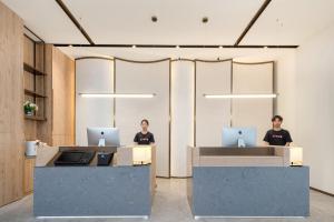 two women sitting at desks in an office with laptops at Atour X Hotel Hangzhou Wenyi Road in Hangzhou