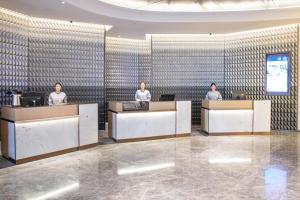three people sitting at reception desks in a lobby at Atour Hotel Suqian Industrial Park Wuyue Plaza in Suqian