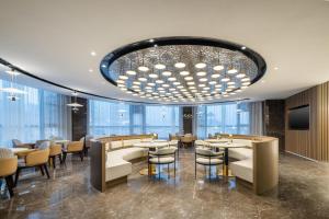 a restaurant with tables and chairs and a chandelier at Atour Hotel Xinghua Dainan in Xinghua