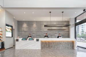a lobby with three men standing at a counter at Atour Hotel Dali Erhai Park in Dali