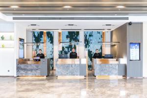 a lobby with three people sitting at reception desks at Atour Hotel Suqian West Lake Road Golden Eagle Plaza in Suqian