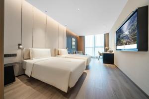 重慶市にあるAtour Hotel Chongqing Liangjiang District Jinke Centerのベッド2台、薄型テレビが備わるホテルルームです。