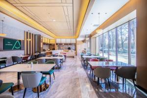 Atour X Hotel Shenyang Beiling Park في شنيانغ: مطعم بطاولات وكراسي ونوافذ