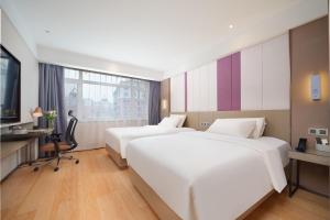 a hotel room with two beds and a desk at Atour X Hotel Dalian Jinzhou Railway Station in Jinzhou