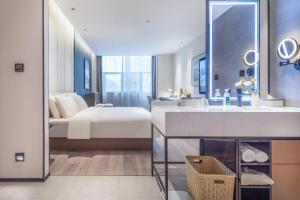 une salle de bain avec une chambre avec un lit et un lavabo dans l'établissement Atour Hotel Suqian West Lake Road Golden Eagle Plaza, à Suqian
