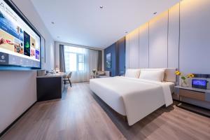 1 dormitorio con 1 cama blanca grande y TV de pantalla plana en Atour Hotel Shanwei High-Speed Railway Station Binhai Park, en Shanwei