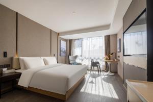 a bedroom with a large white bed and a desk at Atour Hotel Xinghua Dainan in Xinghua