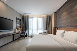 een hotelkamer met een groot bed en een televisie bij Atour X Hotel Suzhou Xiangcheng Vigorous Island Subway Station in Suzhou