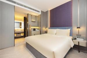a bedroom with a large white bed and a bathroom at Atour X Hotel Shanghai Hongqiao National Exhibition Qibao Old Street in Shanghai