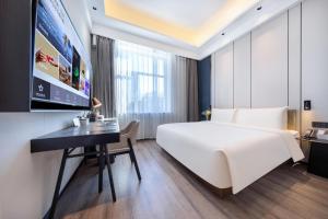 Atour X Hotel Shenyang Beiling Park في شنيانغ: غرفة الفندق بسرير كبير ومكتب