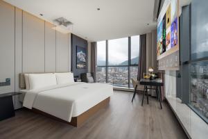 a bedroom with a large white bed and a desk at Atour Hotel Dali Erhai Park in Dali