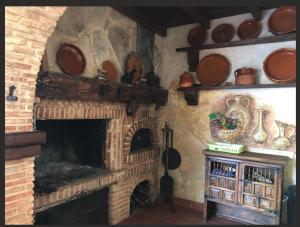 casa rural LAS CHIMENEAS في Casasimarro: غرفة معيشة مع موقد من الطوب وأطباق على الحائط