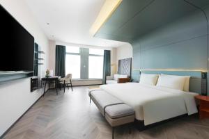 Atour S Hotel Lanzhou Asia-Europe International High Altitude في لانتشو: غرفة نوم بسرير ابيض كبير واريكة
