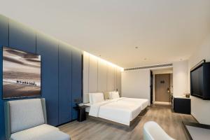a bedroom with a white bed and a tv at Atour Hotel Luqiao Taizhou in Taizhou