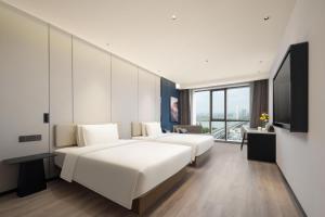 a hotel room with two beds and a flat screen tv at Atour Hotel Nantong Longxin Plaza in Nantong