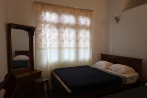 a bedroom with a bed and a window with a mirror at Paramount Hotel Pussellawa in Pussellawa