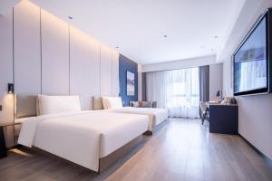 a hotel room with two beds and a flat screen tv at Atour Hotel Suqian Industrial Park Wuyue Plaza in Suqian