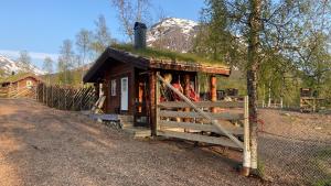 a small cabin with a grass roof and a fence at Bardu Huskylodge 