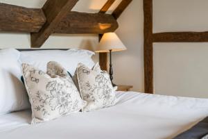 a bedroom with a bed with white sheets and pillows at Box Cottage in Broadwell