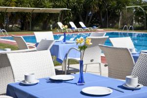 a blue table with plates and flowers on it next to a pool at Palatino Hotel in Lixouri