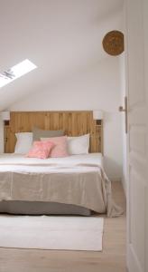 um quarto branco com uma cama grande e almofadas cor-de-rosa em Maison calme - Frontière Montagne et Plage em Urrugne