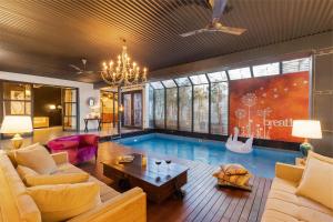 una sala de estar con una piscina en el medio. en StayVista's The Barn House - Farm-View Villa with Modern Rustic Interiors, Indoor Pool & Bar, en Chandīgarh