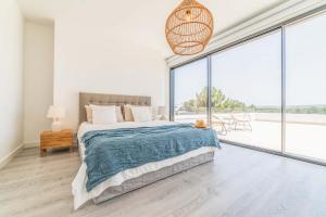 a white bedroom with a bed and large windows at Villa Arrabida in Quinta do Conde