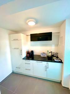 a kitchen with white cabinets and a black counter top at Ferienwohnung direkt am Bodensee / Untersee nahe Konstanz in Berlingen