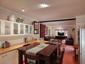 a kitchen with a table and a living room at Khalila's Equestrian Cottage in Midrand