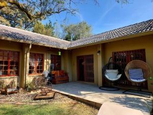 a house with a porch with a wicker chair and a swing at Khalila's Equestrian Cottage in Midrand