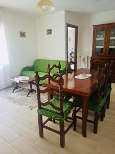uma sala de jantar com uma mesa e um sofá verde em Casa Tatone em Roccaraso